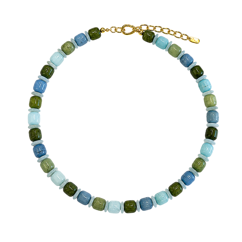 A beaded necklace with alternating light blue, olive green, and medium blue faceted beads, finished with a gold clasp and extender chain, shown on a plain white background.